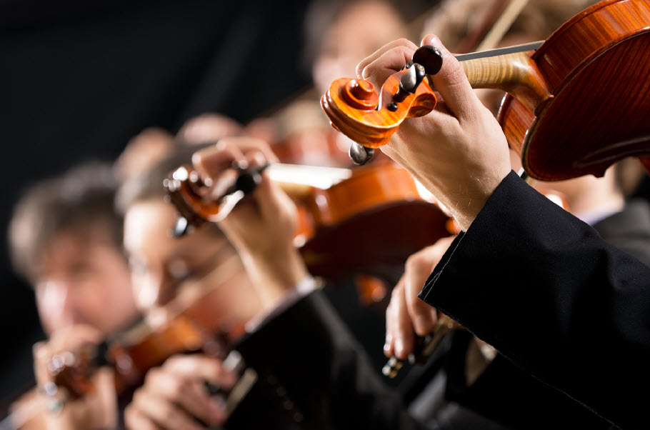 Closeup of strings section of an orchestra playing.