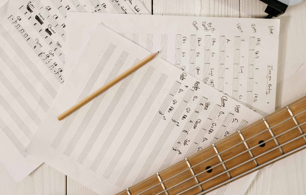 Sheet music, a pencil and a guitar neck.