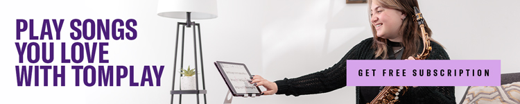 A woman playing saxophone and using a tablet.