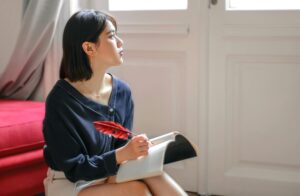 woman writing in notebook and looking off