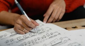 music educator writing notes on musical score 