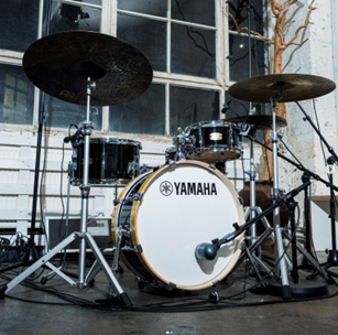 A compact Yamaha drum kit set up outside a house.
