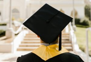 a graduate dressed in cap and gown from behind