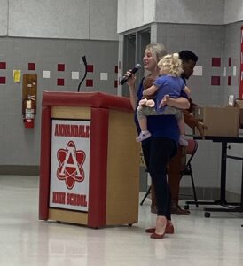 Annie Ray holding daughter while speaking at podium