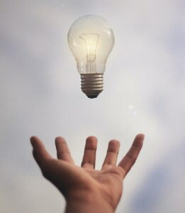 outstretched hand with a lightbulb hovering over it