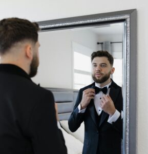man in tuxedo looking in a mirror 