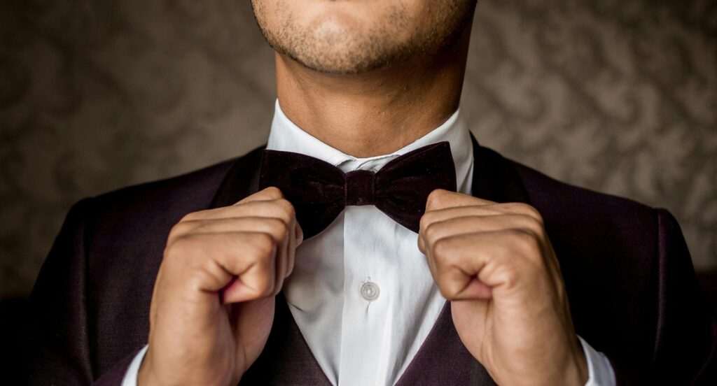 man in tux touching bowtie