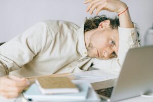 man with his hand on his desk looking exhausted 