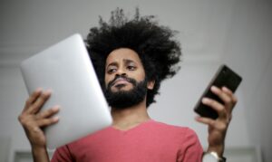 frazzled man holding tablet and cell phone 