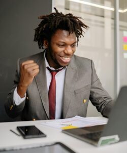 man working at desk and celebrating win with a fist pump