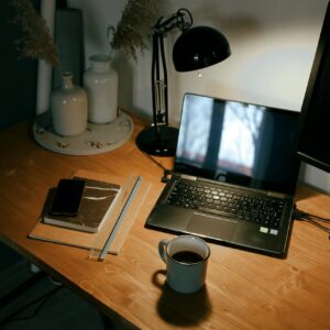 open laptop at night with lamp on and coffee mug on desk 